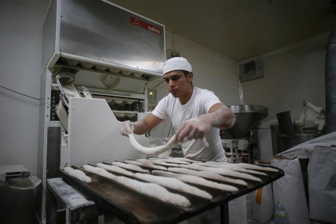 Archivo - Un trabajador prepara barras de pan en el obrador. Imagen de archivo.