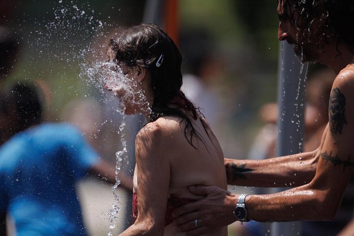 Varias personas juegan en el agua para refrescarse en Madrid Rio