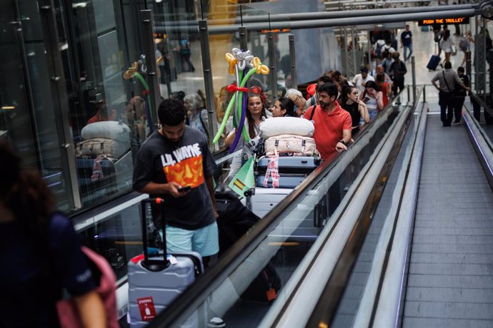 Varias personas en una escalera mecánica de la terminal T4 del aeropuerto Adolfo Suárez-Madrid Barajas, a 30 de junio de 2023, en Madrid (España). 