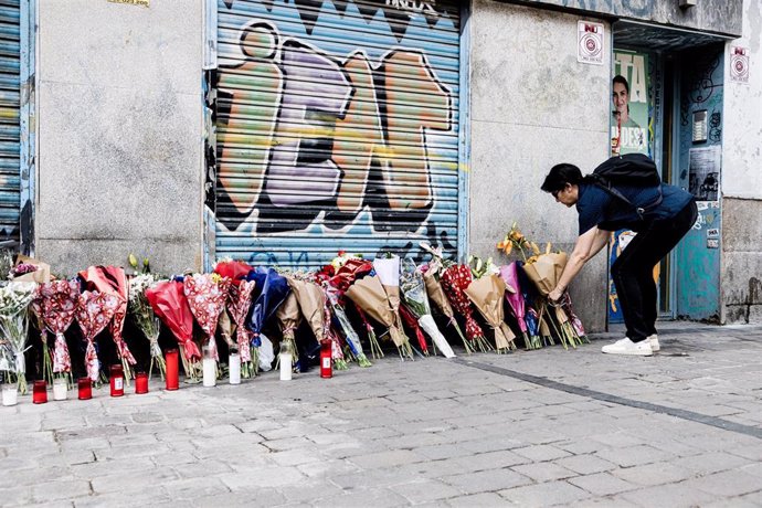 Una mujer deposita un ramo de flores en la tienda de uniformes de trabajo Vistebien, donde el pasado lunes, 3 de julio, apuñalaron a Conchi, la dueña del establecimiento, en la Plaza de Tirso de Molina, a 5 de julio de 2023, en Madrid (España). 