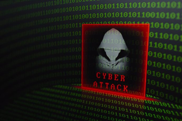 Archivo - Representación visual de un 'hacker' y las palabras ''ciberataque'' sobre un fondo de dígitos de código binario mostrados en una pantalla. 