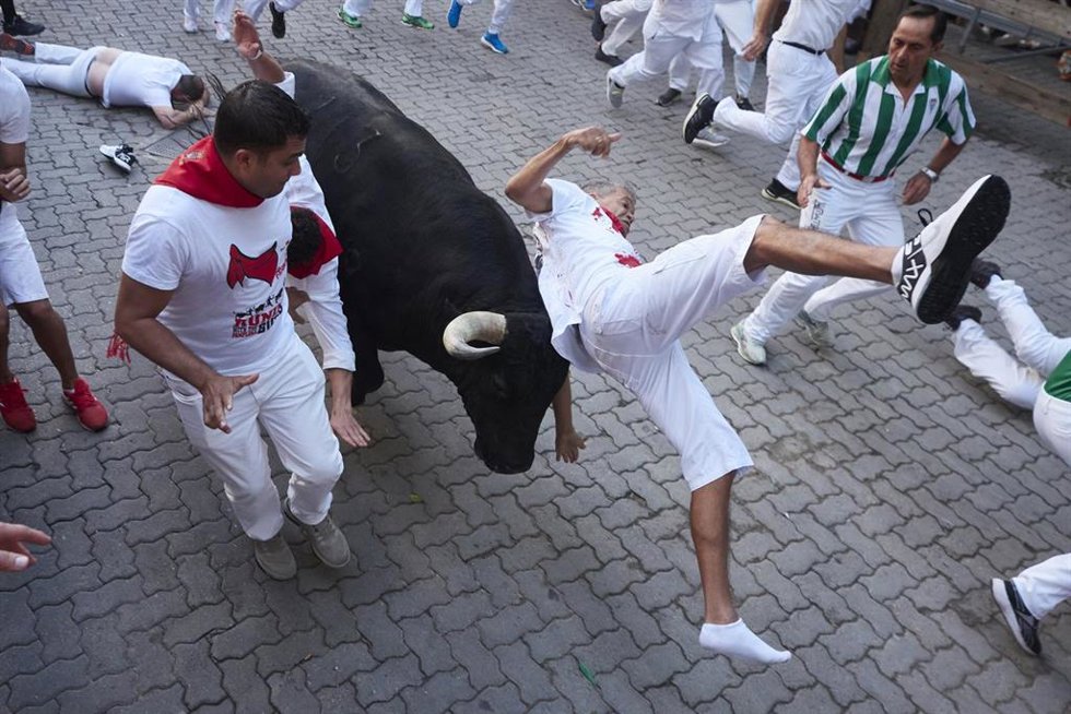 Un toro de Victoriano del Río voltea a un corredor en la bajada al callejón de la Plaza de Toros en el séptimo encierro de los Sanfermines de 2023.