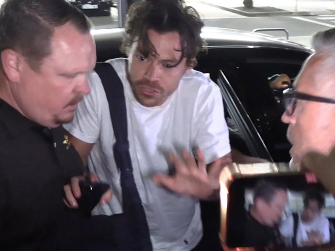 Harry Styles, pidiendo calma a sus escoltas y a sus fans en el aeropuerto de Barceona