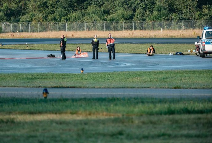 Activistas del grupo Última Generación interrumpen el tráfico aéreo en el aeropuerto de Hamburgo durante una protesta en la que se han pegado en una zona cercana a una pista de aterrizaje