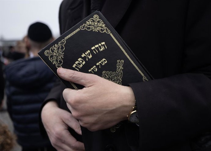 Archivo - Un hombre sujeta una Torá durante un acto previo a la Pascua Judía en Nueva Jersey, EEUU
