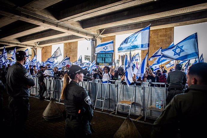July 11, 2023, Jerusalem, Israel: Protestors wave the Israeli flags and hold a placard during a demonstration at the Ben Gurion international airport. Israeli police have clashed with protesters amid huge demonstrations against the government's controvers