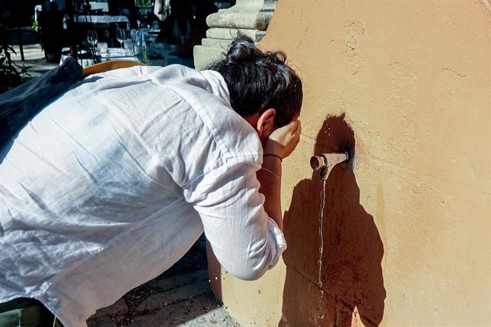 Archivo - Una persona se refresca en una fuente para paliar el calor.