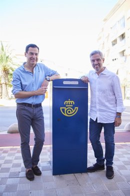 El presidente del PP-A, Juanma Moreno, (i) junto al candidato número uno del PP por Sevilla al Congreso de los Diputados, Juan Bravo, (d) posan junto a un buzón de correos durante la atención a medios de la localidad de Dos Hermanas