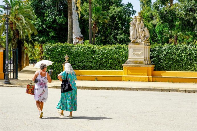 Archivo - Dos mujeres con un paraguas pasean por el Parque de Maria Luisa. Imagen de archivo.