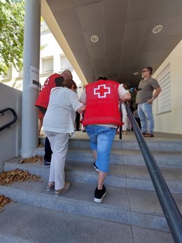 Voluntarios de Cruz Roja acompañan a una persona mayor a votar.