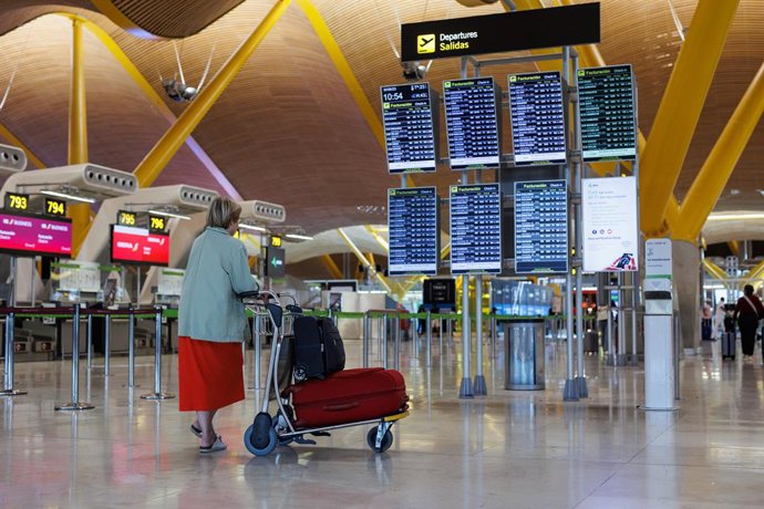 Una mujer con su equipaje frente a un panel de salidas de la terminal T4 del aeropuerto Adolfo Suárez-Madrid Barajas, a 30 de junio de 2023, en Madrid (España).  