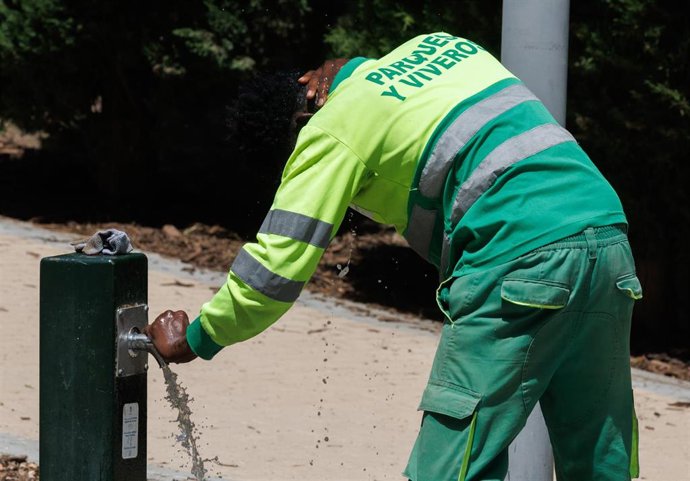 Un trabajador coge agua en una fuente en el Parque del Manzanares, a 11 de julio de 2023, en Madrid.