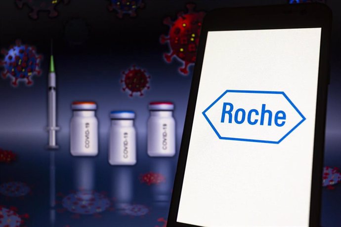 Archivo - 11 November 2021, Paraguay, Asuncion: The logo of Roche is displayed on a smartphone in front of a representation of a medical syringe and ampoules.