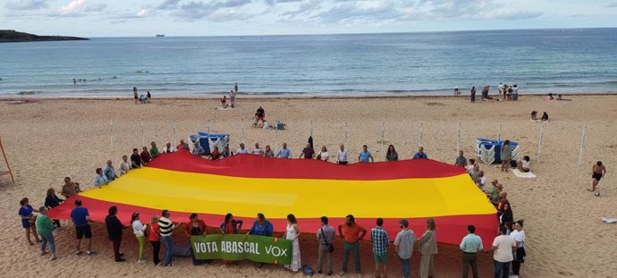 Afiliados y simpatizantes de Vox despliegan una gran bandera de España en la playa de E Sardinero, en Santander