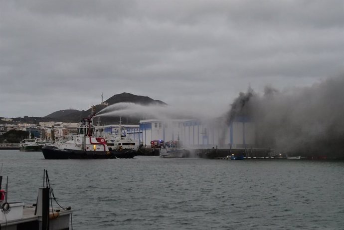 Un barco bombero interviene para intentar sofocar el incendio que ha tenido lugar este jueves en una nave del Puerto de Las Palmas 