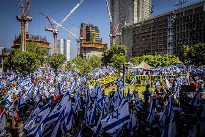 July 18, 2023, Tel Aviv, Israel: Protesters wave the Israeli flag in-front of the workers union building calling on its leader to call for a national strike during a demonstration in Tel Aviv. Tens of thousands of protesters on Tuesday blocked highways an