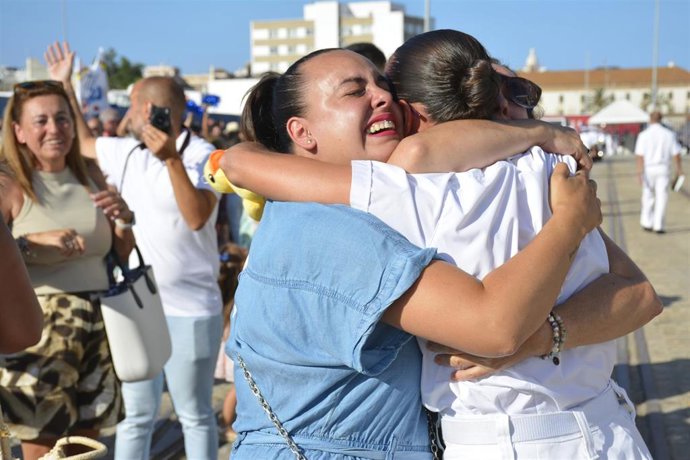 Familiares se abrazan con una tripulante de Elcano en el puerto de Cádiz tras el XCV Crucero de Instrucción .