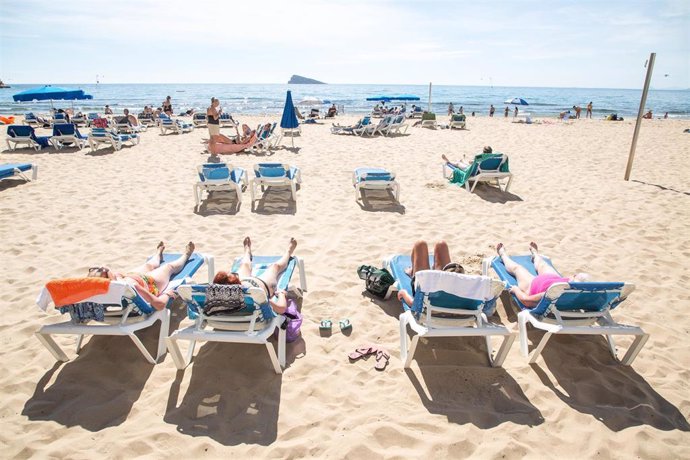 Archivo - Numerosas personas se bañan y toman el sol en la playa de Poniente, en Benidorm