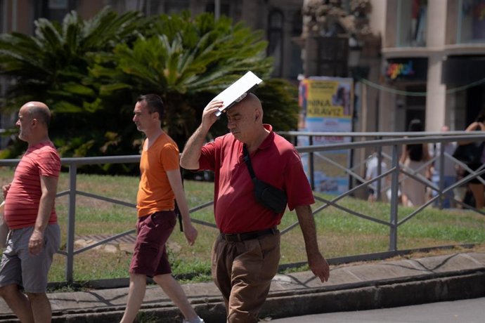 Una persona trata de protegerse del sol en Las Ramblas, a 18 de julio de 2023, en Barcelona, Catalunya (España). 