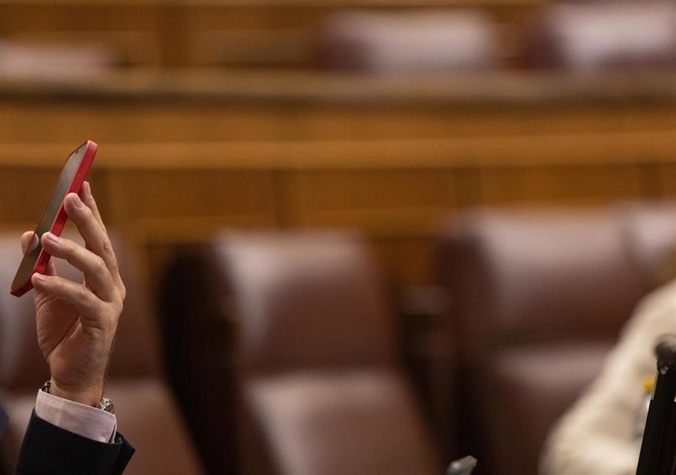 Archivo - Un diputado con su móvil durante una sesión plenaria en el Congreso de los Diputados.
