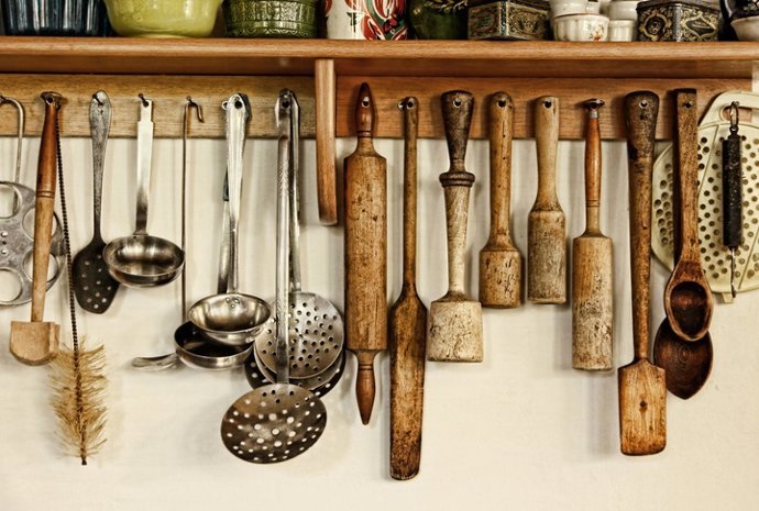 Archivo - Different kitchen ware hanging on the white wall.