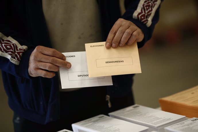 Archivo - Un elector amb els sobres de votació per a les generals