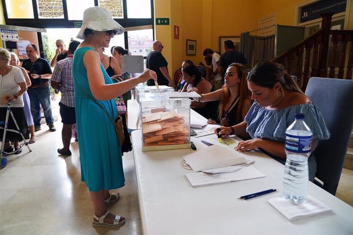 Varias personas cogen papeletas para ejercer su derecho a voto durante las elecciones generales, a 23 de julio de 2023, en Málaga (España)