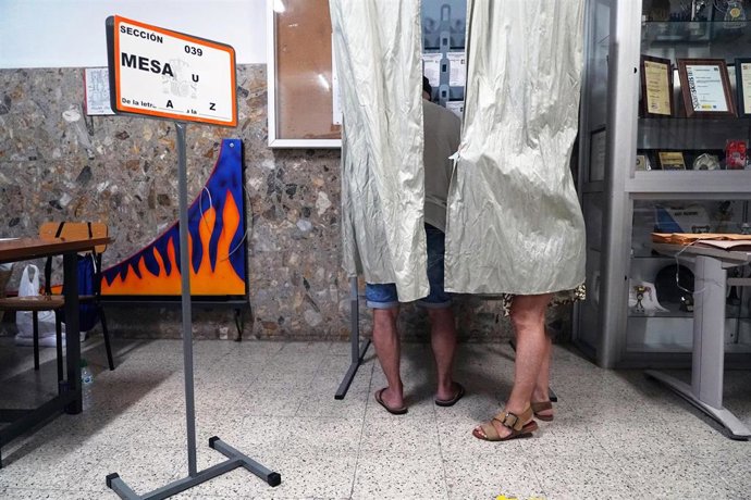 Varias personas cogen papeletas para ejercer su derecho a voto durante las elecciones generales, a 23 de julio de 2023, en Málaga (España). Los españoles están llamados hoy, 23 de julio de 2023, para elegir a sus representantes para los próximos cuatro 