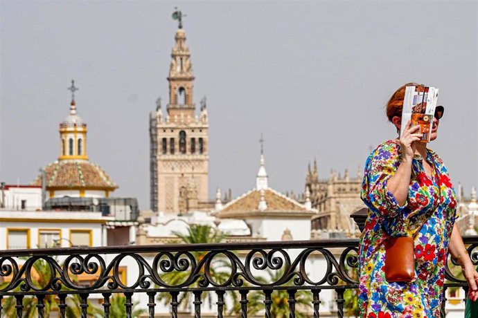 Una persona paseando por el Puente de Triana se protege la cara el día en que la capital está en alerta naranja por el calor , a 19 de julio del 2023. 