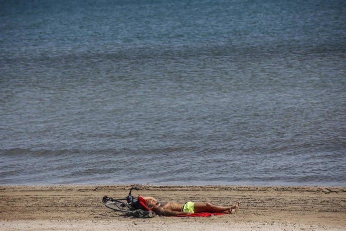 Archivo - Un hombre toma el sol en la playa de La Malvarrosa en imagen de archivo