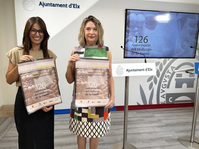 La concejala de Cultura del Ayuntamiento de Elche, Irene Ruiz, y la presidenta de la Real Orden de la Dama, Mari Carmen Pérez Cascales, con el cartel del 126 aniversario del hallazgo de la Dama de Elche.