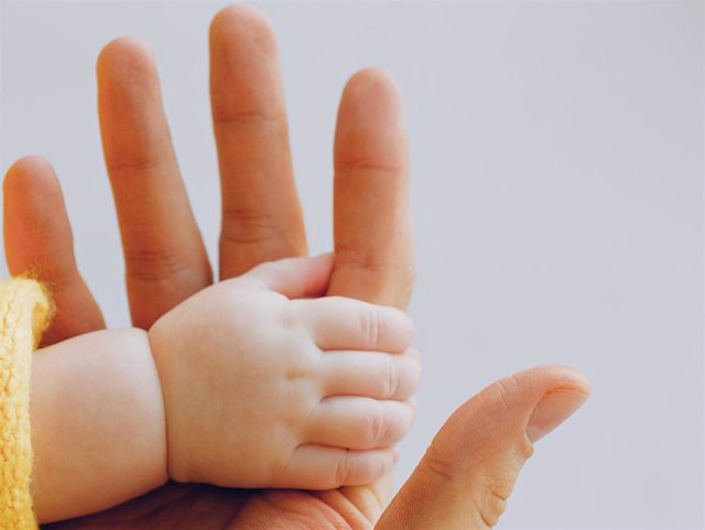 Un adulto con la mano de un bebé