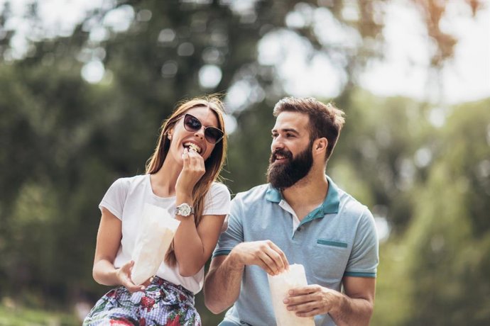Archivo - Pareja comiendo un psicolabis en un parque.
