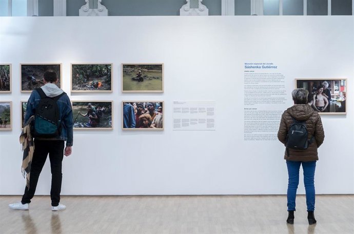 Archivo - Varias personas observan algunas de las obras de la ceremonia de entrega del 26 Premio Internacional de Fotografía Humanitaria Luis Valtueña.