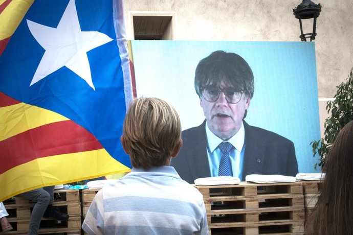 Un niño observa la intervención telemática de Puigdemont en el mitin central del partido JxCAT, a 16 de julio de 2023, en en Amer, Girona, Catalunya (España). Junts per Catalunya ha elegido la ciudad natal del expresidente de la Generalitat y de la form