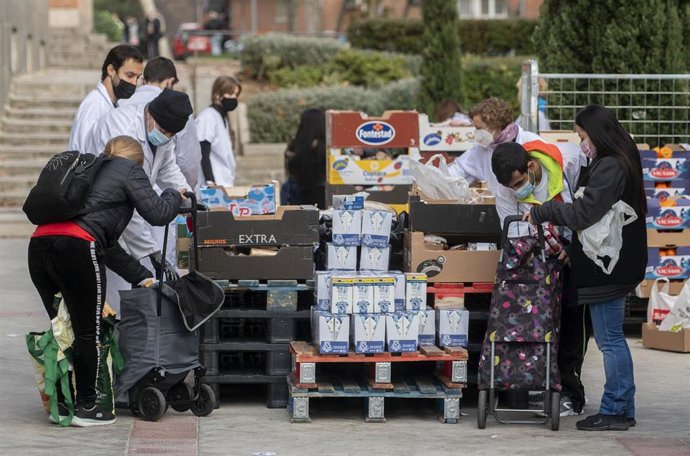 Archivo - Varias personas recogen comida de la Fundación Madrina.