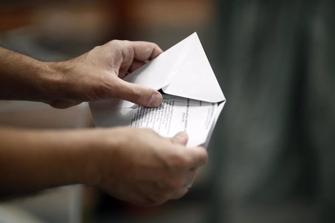 Archivo - Una persona introduce una papeleta electoral en un sobre.