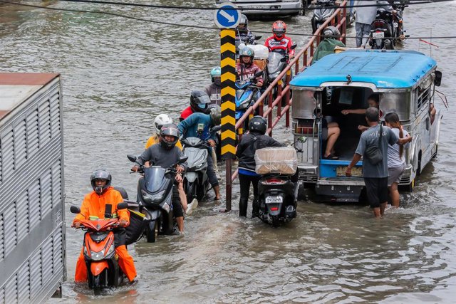 VALENZUELA CITY, July 28, 2023  -- People ride on a waterlogged road in Valenzuela City, the Philippines, July 28, 2023. The death toll from heavy rains, floods, and landslides triggered by typhoon Doksuri has climbed to 13, and 20 more are missing, the P