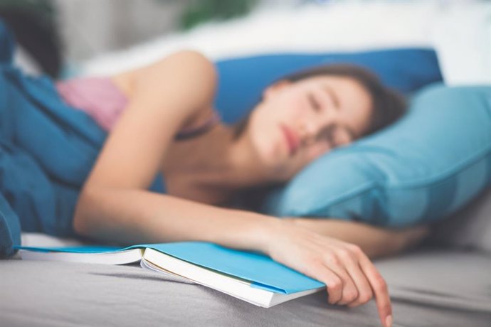 Mujer dormida en la cama después de leer un libro.