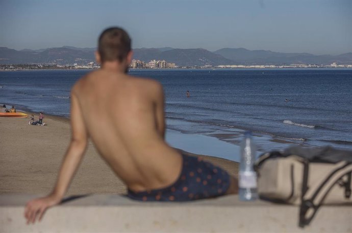 Archivo - Un chico en bañador toma el sol en la playa, a 24 de diciembre de 2022, en Valncia, imagen de archivo