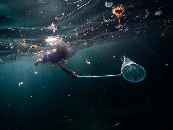 Una voluntaria retira residuos del mar.