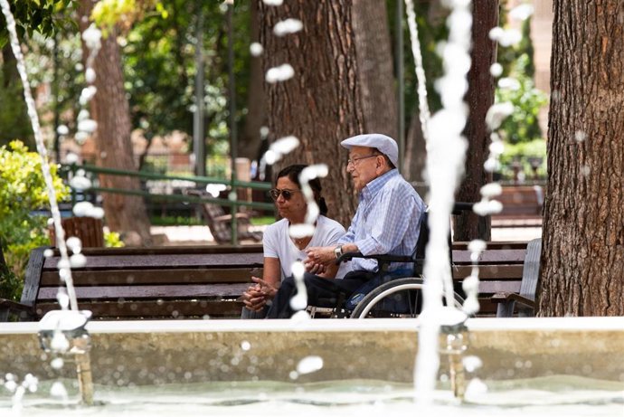 Una mujer y un hombre de avanzada edad descansan al lado de una fuente en el parque Abelardo Sánchez, a 11 de julio de 2023, en Albacete, Castilla-La Mancha (España).