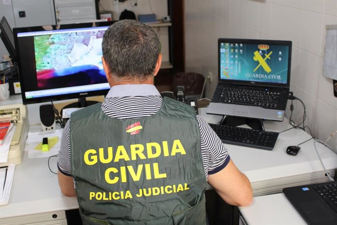 Archivo - Un agente de la Guardia Civil inspecciona archivos en un ordenador