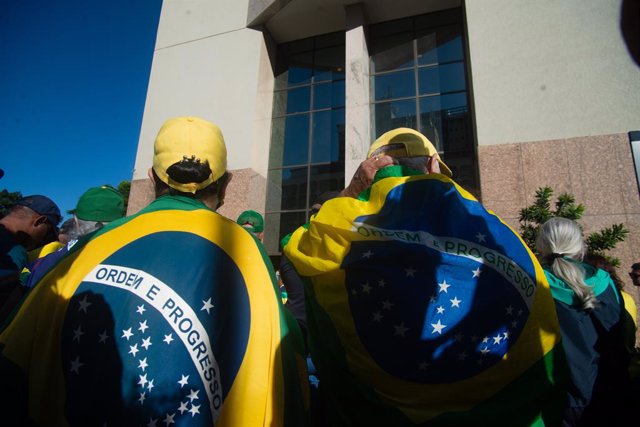 Archivo - 30 March 2023, Brazil, Brasilia: Supporters of former President Jair Bolsonaro stand wrapped in Brazilian flags in front of the hotel where Bolsonaro is staying after his return from the United States. Photo: Matheus Alves/dpa