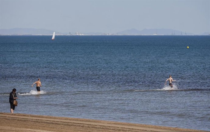 Archivo - Dos personas se bañan en la playa de La Malvarrosa en imagen de archivo