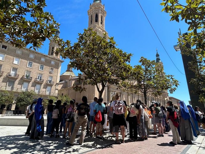 Un grupo de peregrinos de la JMJ visita la plaza del Pilar de Zaragoza, con la Basílica al fondo.