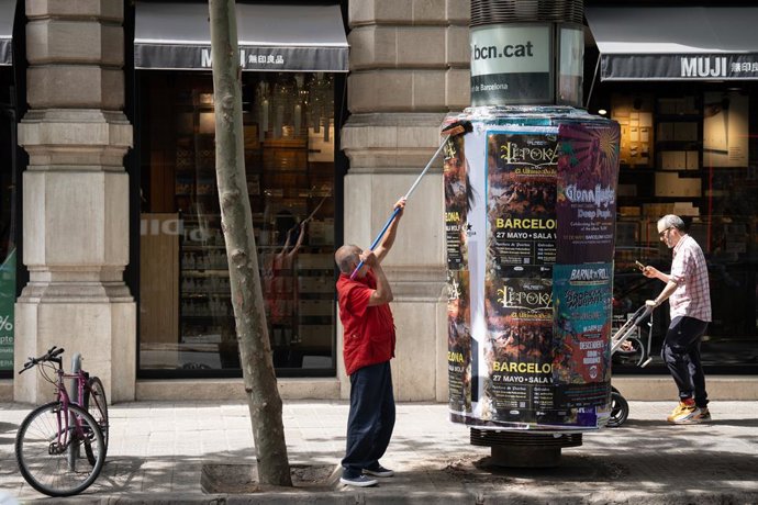 Archivo - Arxivo - Un operari pega cartells, a 10 de maig de 2023, a Barcelona