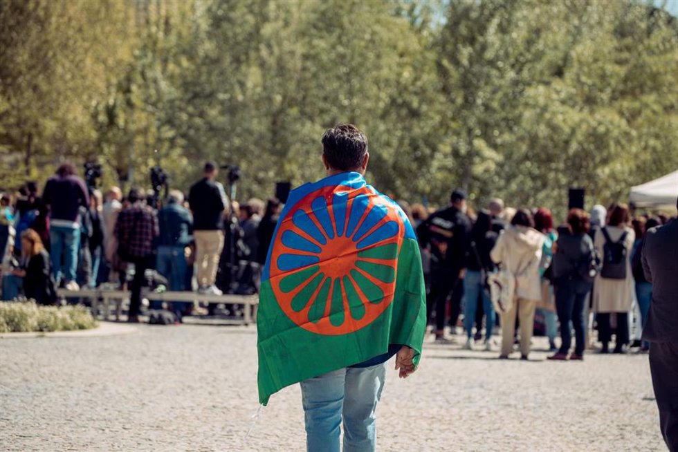 Archivo - Una persona con una bandera gitana a su espalda durante el acto conmemorativo del Día Internacional del Pueblo Gitano