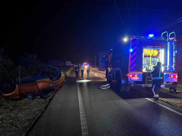 El coche implicado en el accidente, volcado en la carretera.