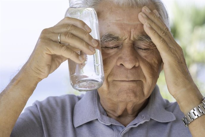 Hombre intentando enfriarse con una botella de agua.